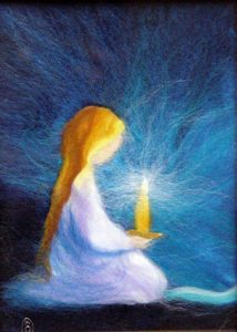 A wool felted depiction of a girl holding a candle in the darkness